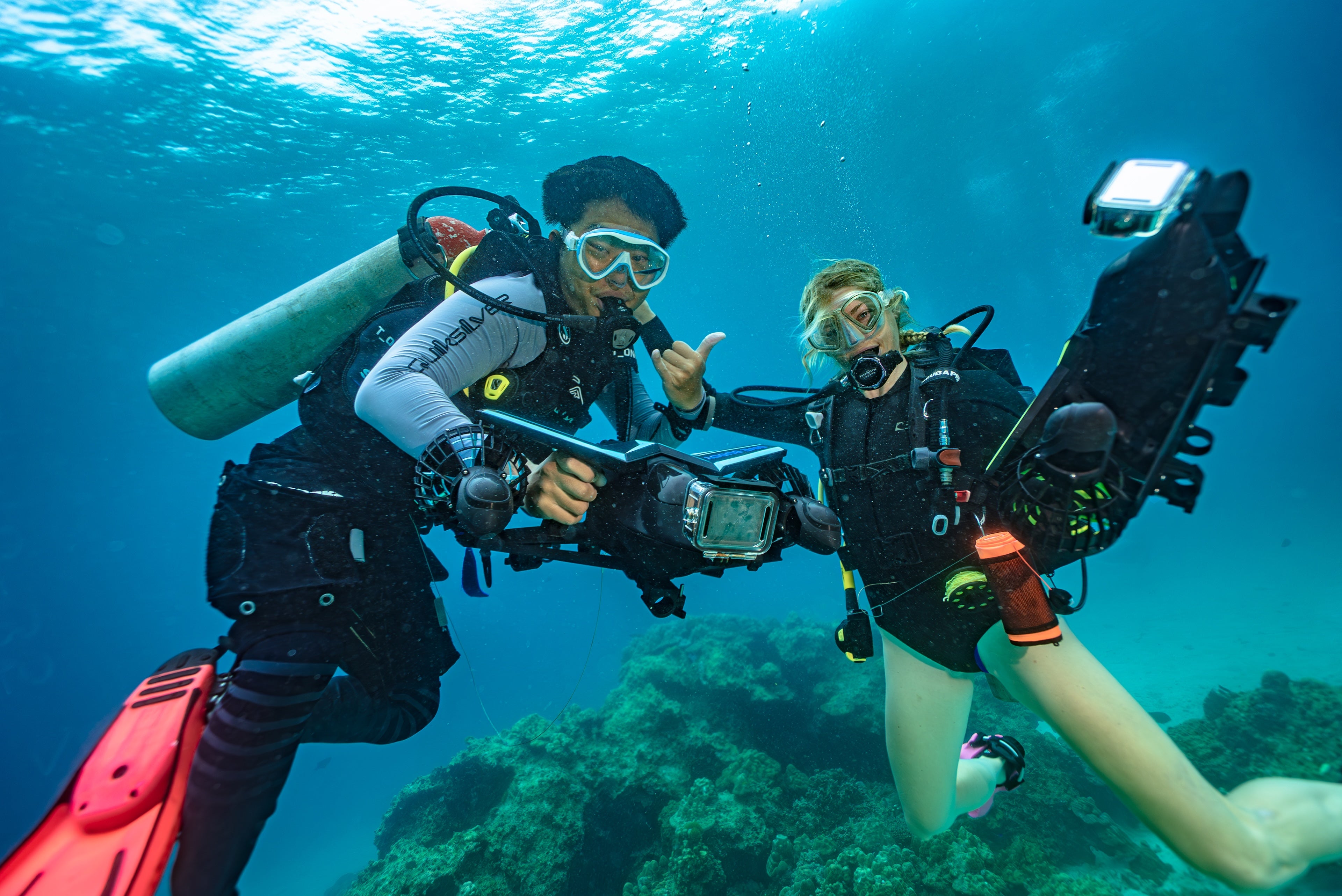 Load video: Video showing two experienced divers and snorkellers performing underwater manouvers gliding around the reefs free-diving and later with full scuba equipment diving on wrecks and reef using the DiveBuddy Seascooter to see much of the reef and sunken boat wreck. The action show how easy the underwater scooter is to use to cover distances quickly and explore the underwater scene.